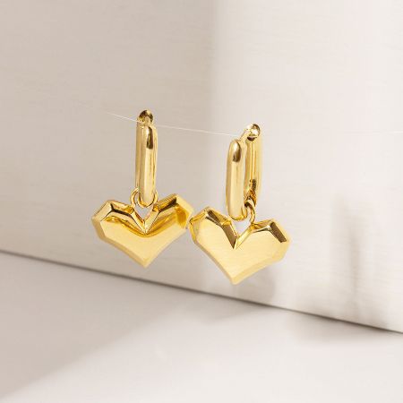 Close-up view of the shiny gold heart-shaped huggie earrings.
