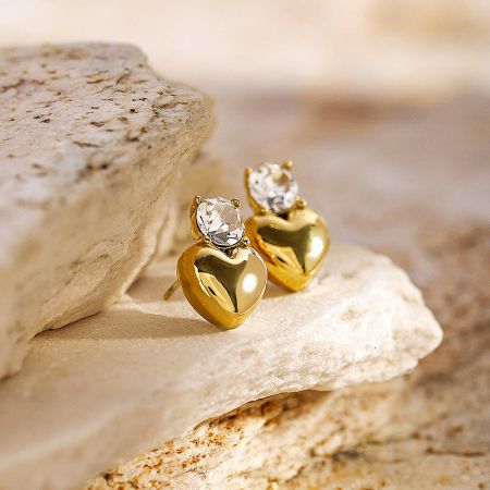 Another angle of the gold heart-shaped earrings with clear gemstones.