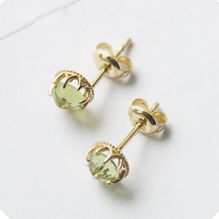 Close-up of heart-shaped peridot stud earrings with 18K gold plating.