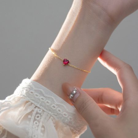 Close-up of the gold heart zircon bracelet, highlighting the delicate chain and sparkling pink gemstone.