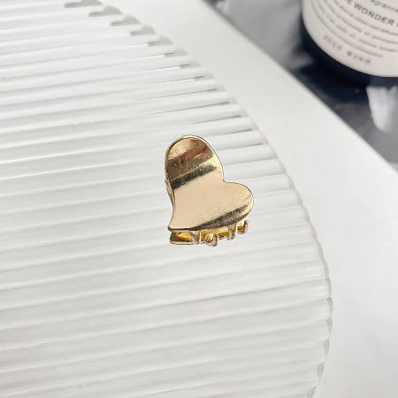 A delicate gold heart-shaped mini hair claw clip shown up close.