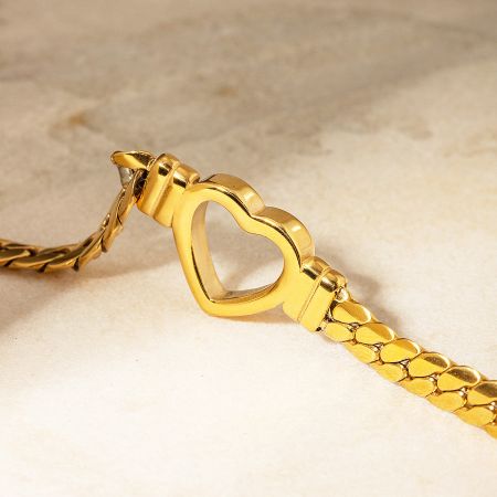 Macro shot of the intricate gold heart-shaped jewelry clasp.