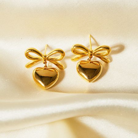 A pair of gold heart-shaped earrings with delicate bow details.