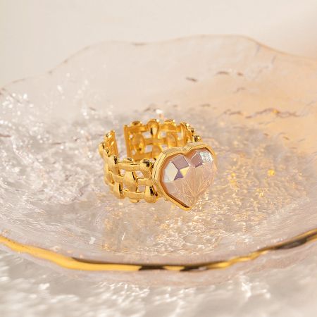The gold heart ring displayed on a decorative surface, highlighting its shine.