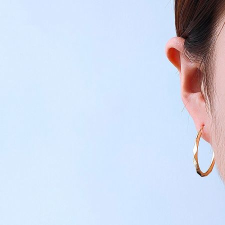 28mm Infinity Hoop Earrings - A close-up view of a woman wearing the 28mm Infinity Hoop Earrings, showcasing their elegant gold finish and classic style.