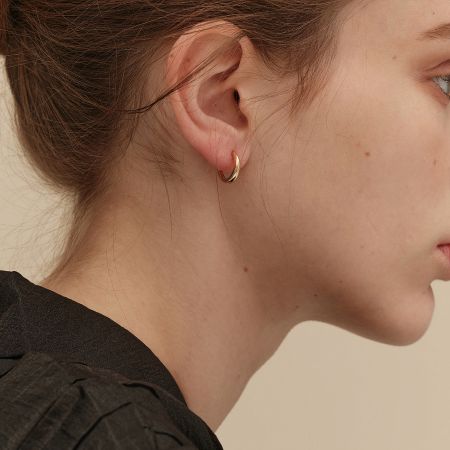 Close-up of a model wearing the 18K gold plated hoop earring, highlighting its smooth texture and brilliant shine.