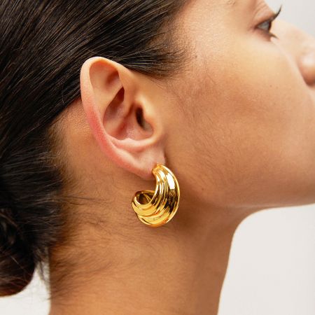 Close-up of a model wearing the chunky gold C-shaped hoop earring, showcasing its fit and style.