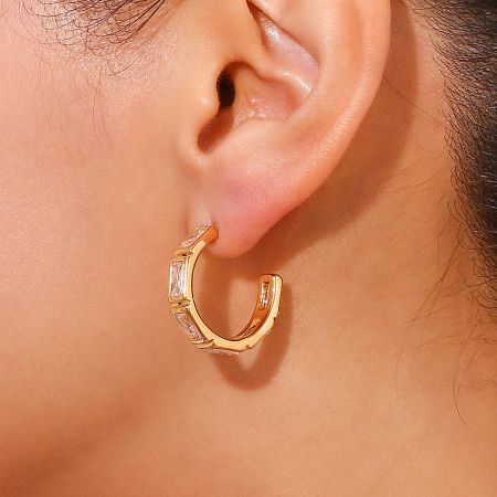 Close-up view of the gold bamboo hoop earring with classic white zircon stones on a model.