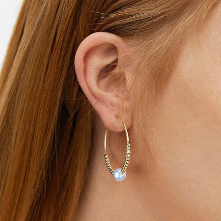 Side profile of a model wearing the gold pearl hoop earring, highlighting its shine and detail.