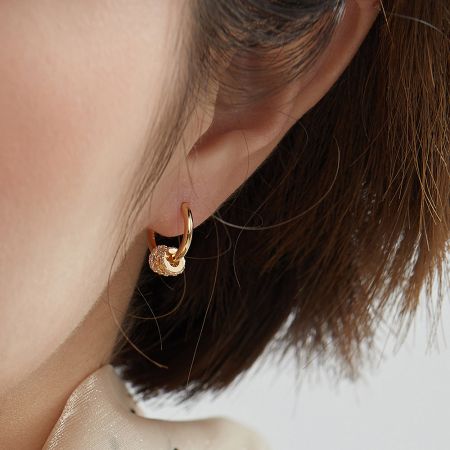 A detailed shot of the gold hoop earring, focusing on the decorative element with small stones.