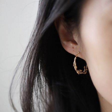 Model showcasing the elegant fit of the gold-plated leaf branch stud earring.