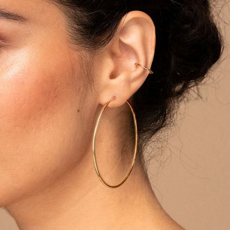 Detailed close-up of the large gold hoop earring's finish and clasp.