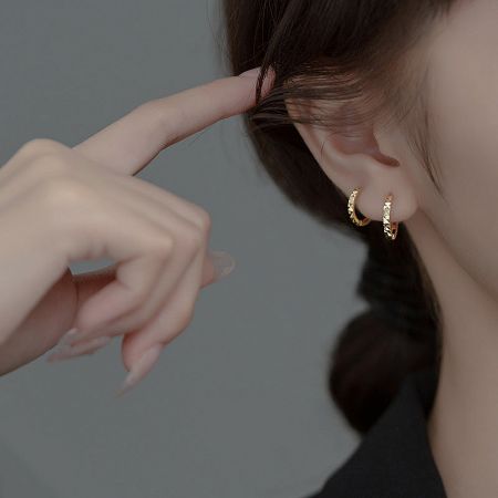 Model showcasing the elegant fit of the gold huggie hoop earring for a chic look.