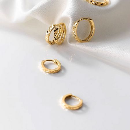 Detailed shot of the textured gold hoop earrings.