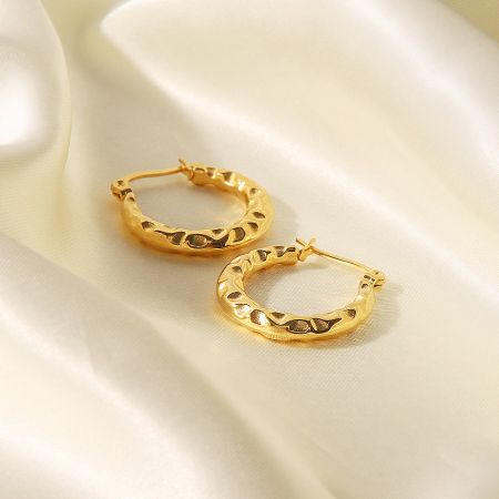 Front view of the textured gold hoop earrings against a white backdrop.