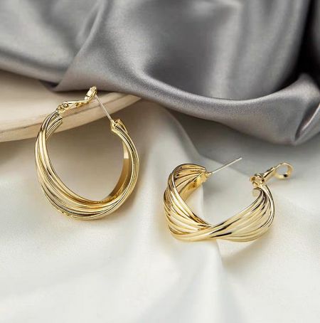 Close-up of the intricate twisted wire design on the criss-cross gold hoop earrings.