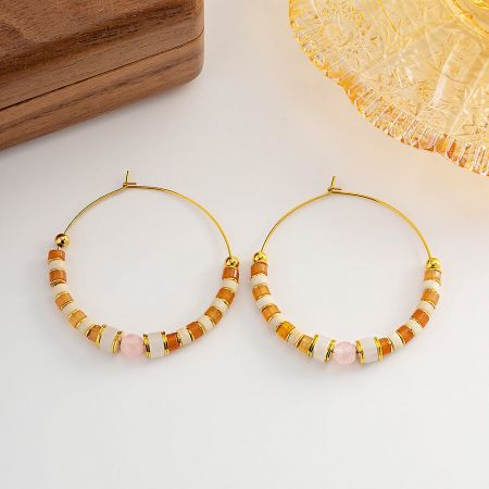 Close-up of beaded hoop earrings featuring cylindrical and spherical beads in soft tones.