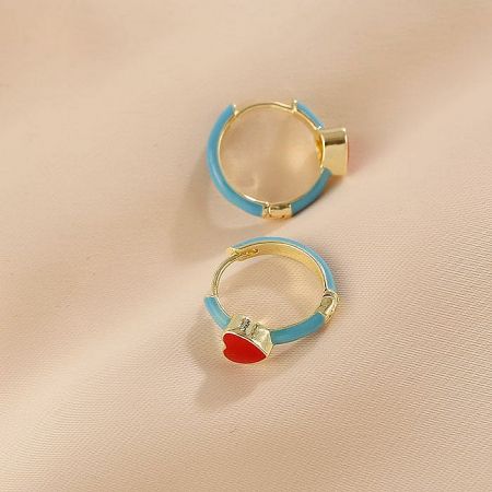 A variation of the huggie hoop earring featuring a dangling red heart charm.