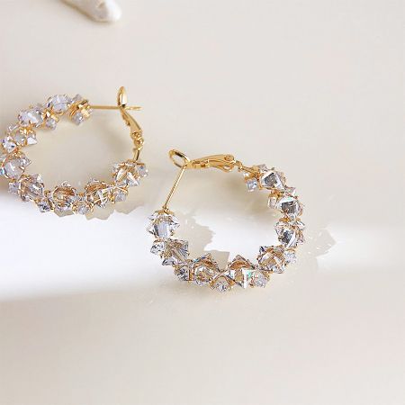 Detailed view of the gold hoop earrings highlighting the clear zircon stones.