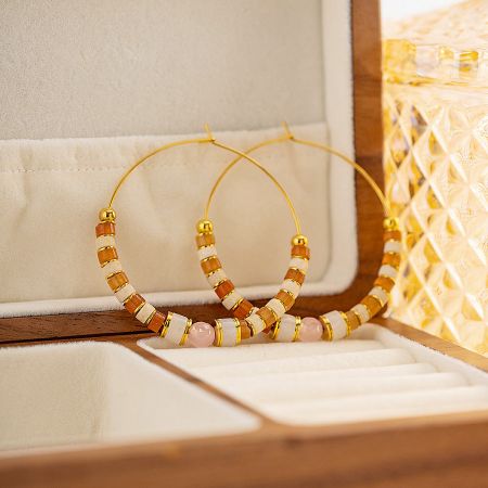 A luxurious presentation of colorful beaded gold hoop earrings in a display box.