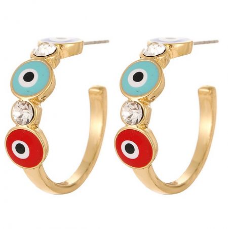Detail shot of gold hoop earrings adorned with turquoise, red, and white circular enamel designs and clear crystals.