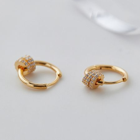 Close-up of the circular design of the gold hoop earrings with small encrusted stones.