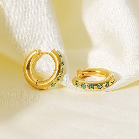 Close-up of the 20mm gold hoop earrings with vibrant green cubic zirconia stones.