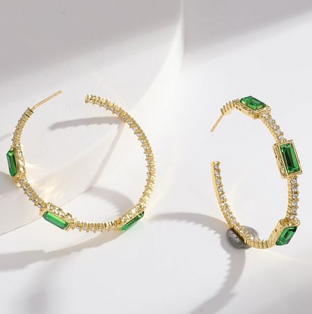 Angled shot of the Emerald Green CZ Hoop Earrings highlighting the sparkle of the crystals.