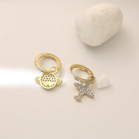 Full view of the gold hoop earrings with delicate planet and star charms.