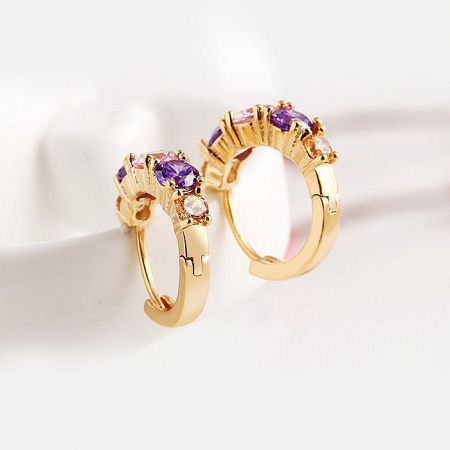 Close-up of the gold hoop earring showcasing purple and clear cubic zirconia stones.