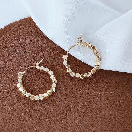 Detailed view of the gold hoop earrings with small, square crushed stone beads.