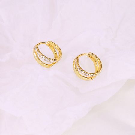 Detailed view of the gold hoop earrings featuring sparkling white stones.