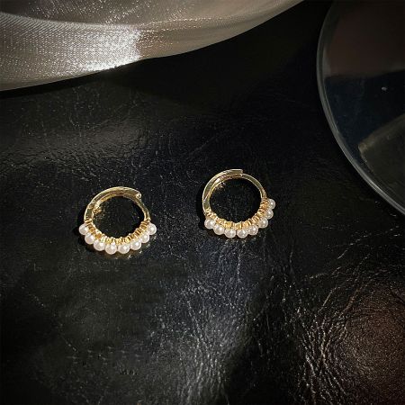 Detailed view of a pair of gold hoop earrings with delicate pearl accents.