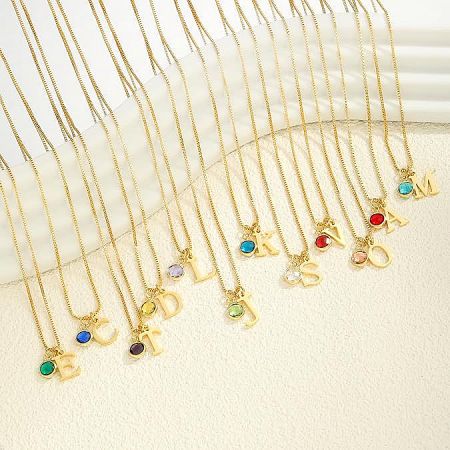 A collection of customizable gold initial necklaces with various colored gemstones.