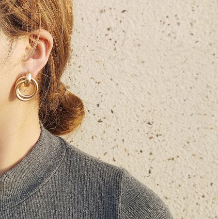 Close-up of the geometric knot cord stud earring on a model's ear, highlighting the matte finish.