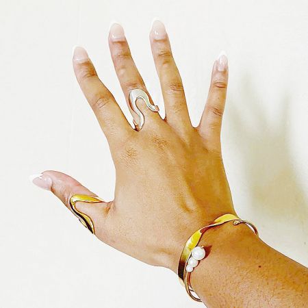 Close-up of a hand modeling the unique gold geometric rings and a matching bracelet.