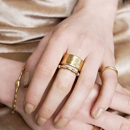 Model's hands showcasing multiple gold rings and bracelets from the collection.