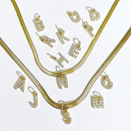 An assortment of gold letter charms and necklaces, highlighting the product variety.
