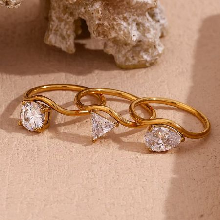 Close-up of the wavy gold-plated stainless steel rings with clear zircon stones.