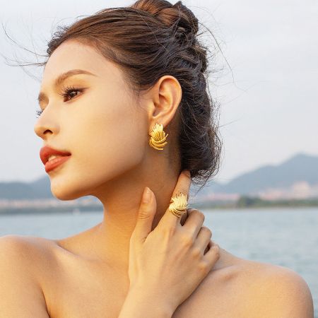 Lifestyle image of a woman wearing the 18k gold-plated earrings and matching ring.