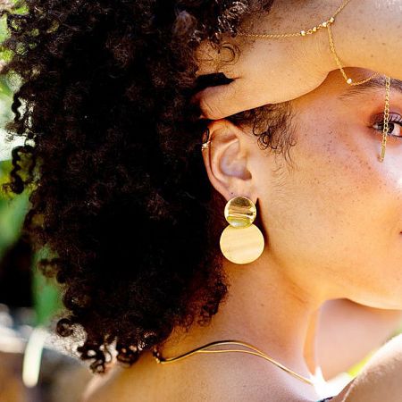 Close-up of a model showcasing the laminated disc drop earrings, highlighting how they complement her style.