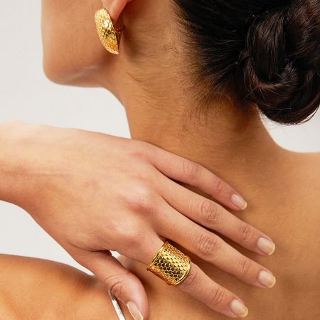 A close-up portrait of a woman wearing the gold snakeskin textured ring and matching earring.