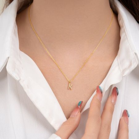 Close-up of the gold letter 'K' pendant, showcasing the intricate zircon setting.