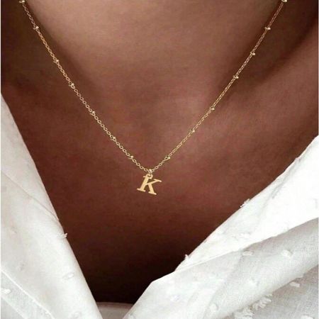 A close-up of the gold 'K' initial pendant on the stainless steel necklace.