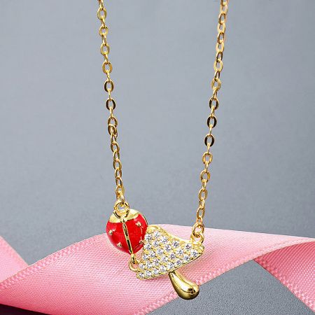 Detailed view of the gold-plated sterling silver ladybug and leaf pendant necklace from the set.