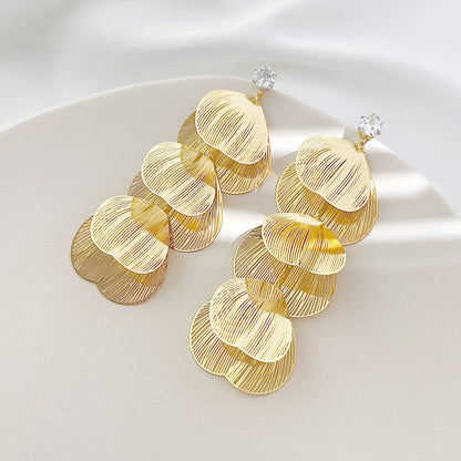 A pair of gold earrings with a delicate, layered floral petal design.