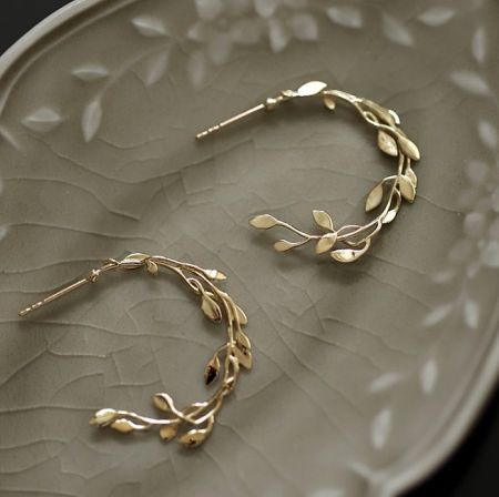 925 Sterling Silver Leafy Hoop Earring - A pair of 925 Sterling Silver Leafy Hoop Earrings with gold plating, displayed on a decorative plate to showcase the intricate leafy branch design and cubic zirconia details.