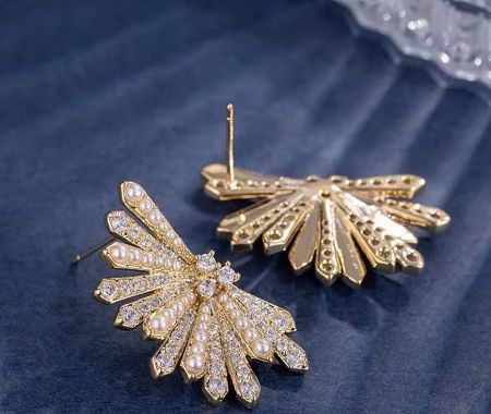 Detailed view of the fan-shaped earrings showcasing the intricate design with pearls and crystals on a velvet background.