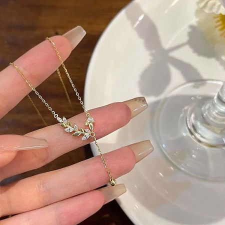 Product image of the gold leaf tassel necklace against a clean white background.