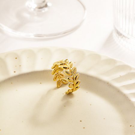 The olive branch leaf ring elegantly displayed on a white surface.